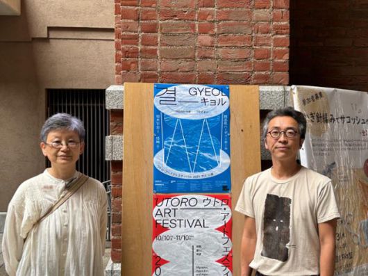 유재현(오른쪽) 우토로 아트 페스티벌 2025 예술감독과 정현주 수석큐레이터가 12일 일본 교토부 교토시 소재 도시샤대에 설치된 페스티벌 포스터 앞에서 기념촬영을 하고 있다. 교토=류호 특파원