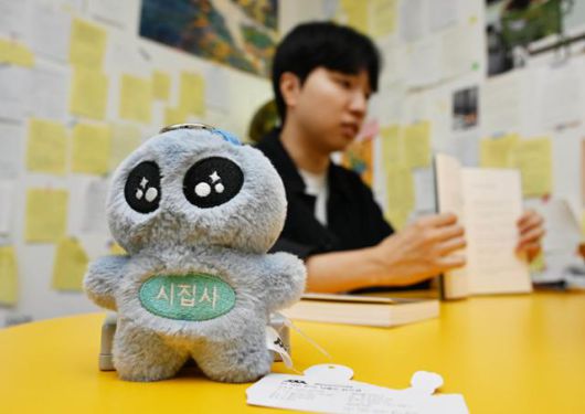 포엠매거진이 제작한 굿즈인 시집사 외계인 키링 뒤로 배동훈씨가 황인찬 시집 '희지의 세계'를 들어보이고 있다. 왕태석 선임기자