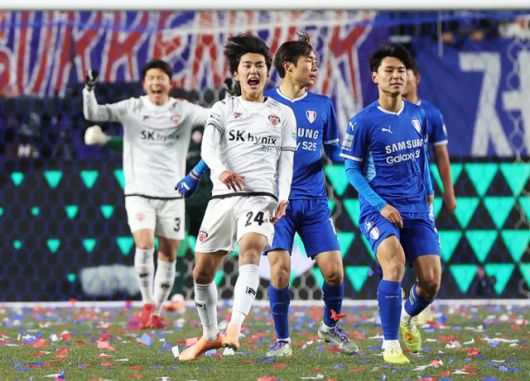 흰색 유니폼을 입은 제주SK 선수들이 3일 수원월드컵경기장에서 열린 수원 삼성과의 K리그 승강 플레이오프 1차전을 1-0으로 승리한 뒤 기뻐하고 있다. 반면 푸른색 유니폼의 수원 선수들은 아쉬운 표정을 짓고 있다. 연합뉴스