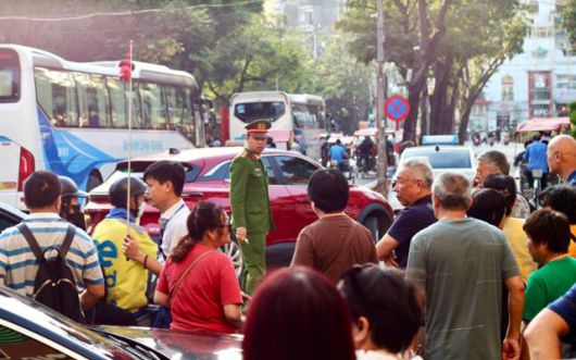 지난 1일 베트남 하노이 관광지인 호안끼엠 호수 인근에서 도로 정리에 나선 교통 공안 앞으로 관광객들이 지나고 있다. 하노이=허경주 특파원