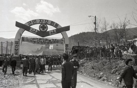 1980년 4월 23일 강원 정선군 사북읍의 광업소 정문을 광부들이 지키고 있다. '증산보국', '노사협조증진강조기간' 등의 글씨가 정문에 적혀있다. 한국일보 자료사진