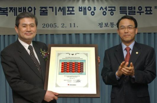 2005년 2월 11일 진대제 정보통신부 장관(오른쪽)이 황우석 교수에게 장애인이 휠체어에서 일어나 안기는 모습을 형상화한 특별우표를 증정하고 박수를 치고 있다. 진대제는 DJ 정부 때 황우석과 함께 국가과학기술자문위원을 맡았고 황금박쥐 멤버로 친목을 다졌다. 한국일보 자료사진