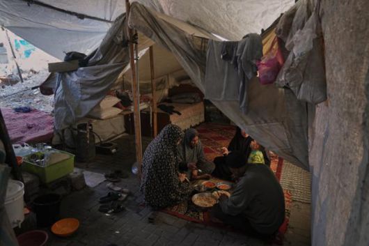 지난해 12월 25일 팔레스타인 가자지구 북부 알샤티 난민촌 천막 안에서 한 피란민 가족이 식사하고 있다. 가자지구=AP 뉴시스