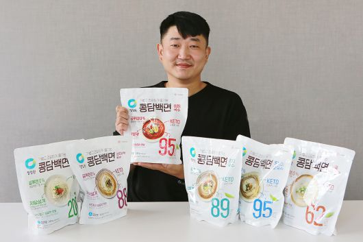 김용건 대상 청정원 식품연구소 수석연구원이 본인이 개발한 콩담백면 제품들과 함께 환하게 미소짓고 있다. 김 연구원이 가장 좋아하는 제품 중 그 중에서도 ‘비빔국수 콩담백면’이라고 한다. [대상 제공]
