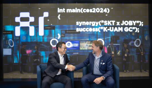 유영상 SK텔레콤 사장(사진 왼쪽), 조벤 비버트 Joby Aviation CEO(사진 오른쪽)가 CES 2024에 마련된 ‘SK ICT 패밀리 데모룸’에서 기념 촬영을 하고 있는 모습. [SK텔레콤 제공]