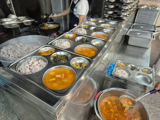 봉사자들이 식판에 미리 밥과 국을 퍼 식사를 준비하는 모습[김도윤 기자]