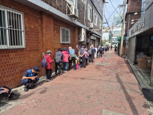 무료급식소 앞에서 식사를 하기 위해 긴 줄을 선 사람들의 모습 [김도윤 기자]