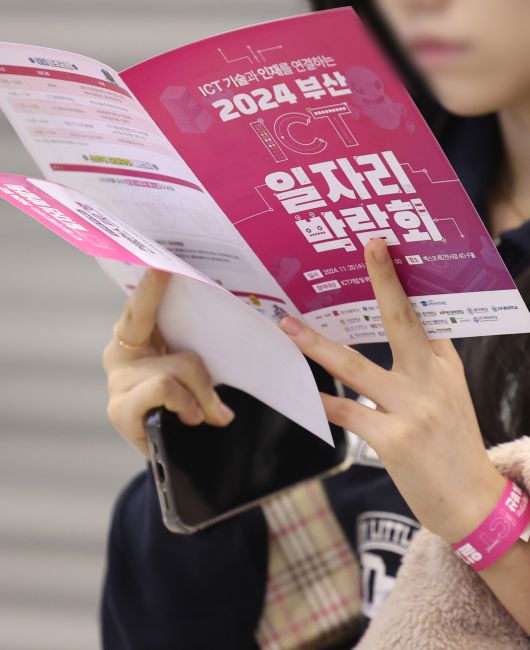 ICT 기술과 인재를 연결하는 2024 부산 ICT 일자리 박람회가 열린 20일 오전 부산 해운대구 벡스코 제2전시장에서 한 구직자가 채용 안내 책자를 살펴보고 있다. [연합]