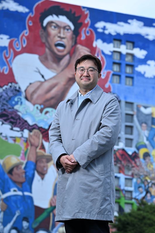 15일 서울 동대문구 경희대학교 문과대학 앞에 선 장문석 경희대 국문과 교수. 배경은 1987년 6월 민주항쟁을 기념해 1989년 완성된 벽화 ‘청년’으로, 민주화운동의 상징으로 여겨진다. [임세준 기자]