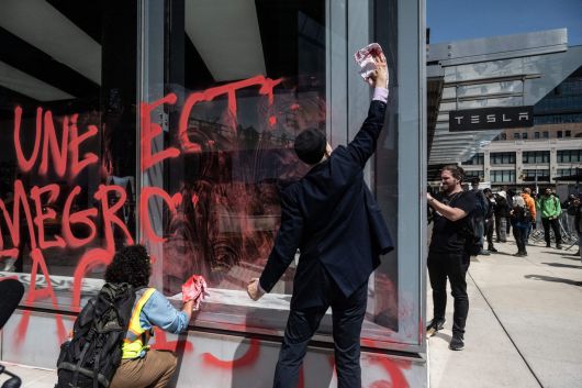 지난 22일(현지시간) 뉴욕의 한 테슬라 매장 외부에 ‘반(反) 정부효율부’ 테러에 직원들이 청소를 하고 있다. [AFP]