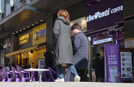 저가 커피 판매점이 밀집한 서울 종로구의 상가 앞으로 시민들이 지나가고 있다. [연합]