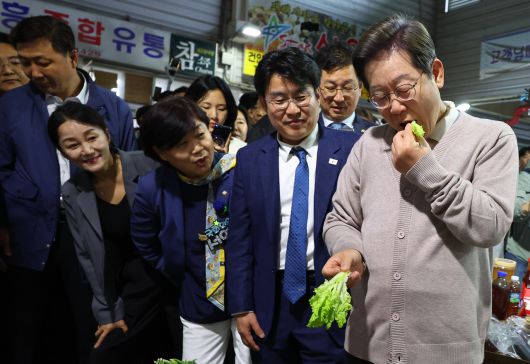 이재명 더불어민주당 대선 후보가 제3차 골목골목 경청투어로 경북지역 방문에 나선 9일 경북 영천시 영천공설시장의 한 가게에서 판매하는 상추를 맛보고 있다. [연합]
