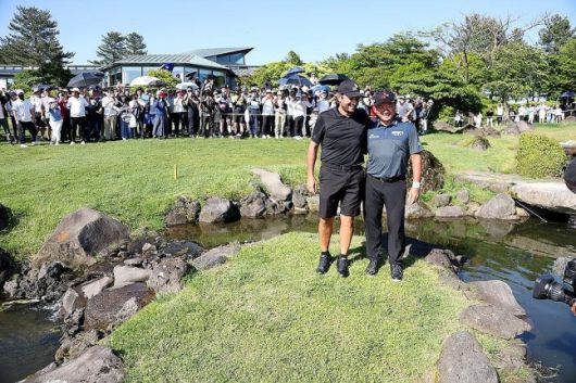 최경주가 지난해 SK텔레콤 오픈에서 정상에 오른 후 우승 발판이 된 18번홀 그린 앞 개울의 섬에서 캐디와 기념 촬영을 하고 있다.    [KPGA 제공]