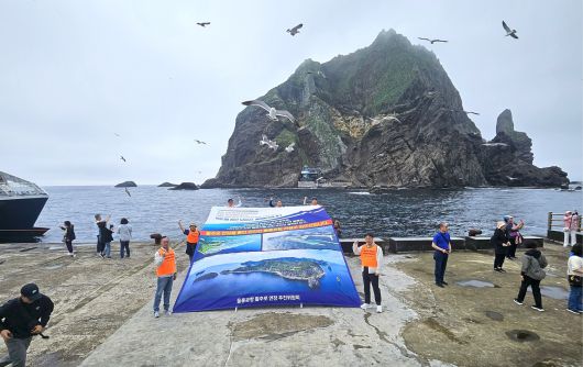 17일 독도 선착장에서 ‘울릉공항 활주로 연장 추진위원회’가 울릉공항 활주로 연장을 촉구하며 현수막을 들고 구호를 외치고 있다.[울릉공항 활주로 연장 추진위원회 제공]