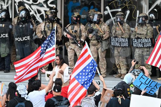 10일(현지시간) 미국 캘리포니아주 로스앤젤레스 연방청사에서 연로스앤젤레스(LA)에서 이어지는 불법 이민자 단속 반대시위가 계속되는 가운데 주방위군 병사들과 연방 경찰관들이 시위대와 대치하고 있다. [AFP]