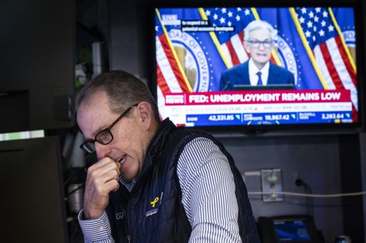 18일(현지시간) 미국 뉴욕증권거래소(NYSE)에서 한 트레이더가 제롬 파월 미 연방준비제도(Fed·연준) 의장의 기자회견 모습이 담긴 TV 화면 밑에서 주식 거래에 집중하고 있다. [EPA]