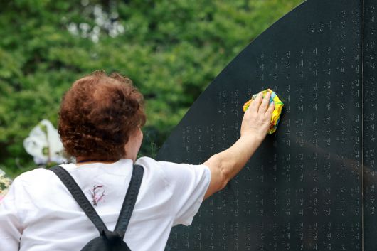 삼풍백화점 붕괴 참사 30주기인 지난 29일 서울 서초구 매헌시민의숲 삼풍참사위령탑을 찾은 유족이 희생자를 추모하며 희생자 이름이 새겨진 위령탑을 손수건으로 닦고 있다. [연합]