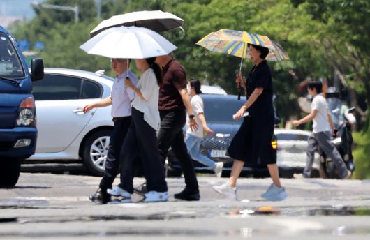 전국 대부분 지역에 폭염 특보가 발효된 3일 광주 서구 치평동에서 시민들이 강렬한 햇빛에 달구어져 아지랑이가 피어오르는 도로를 걷고 있다.[연합]