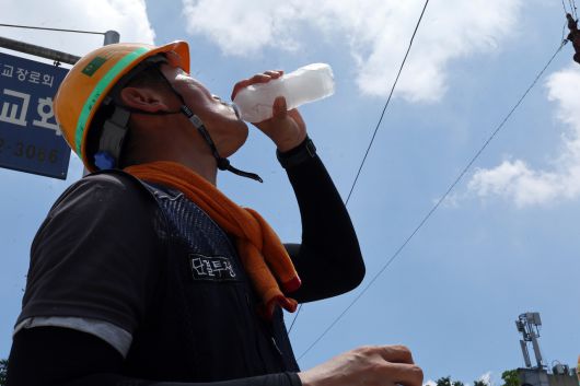 엿새째 폭염특보가 내려진 2일 광주 서구 금호동 한 공사장 앞에서 한 건설노동자가 더위를 달래기 위해 얼음물을 마시고 있다.[연합]
