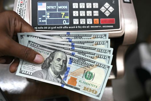 한 환전소에서 근무하는 직원이 미국 달러 지폐를 들고 포즈를 취하고 있다. [AFP]