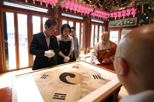 이재명 대통령 내외가 17일 은평구 진관사를 찾았다. 진관사 주지인 법해스님이 호국사찰로 큰 역할을 해온 진관사의 역사를 소개하며 대통령 내외에 진관사의 보물인 태극기를 보여주고 있다. [대통령실]