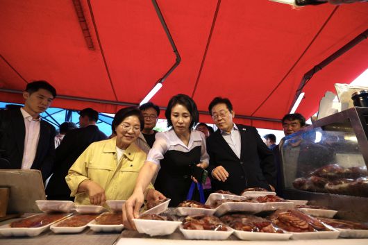 김혜경 여사와 이재명 대통령이 17일 서울 은평구에 위치한 연서시장을 찾아 구매할 음식들을 고르고 있다. [대통령실]