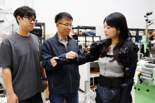 박철훈(가운데) 박사가 경량 의복형 웨어러블 로봇을 살펴보고 있다.[한국기계연구원 제공]