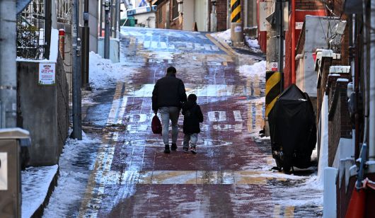 전날 내린 폭설과 계속되는 한파로 도로 곳곳이 얼어붙은 가운데 5일 오전 서울 용산구 한 이면도로에서 아빠와 아이가 손을 잡고 길을 가고 있다.  이상섭 기자