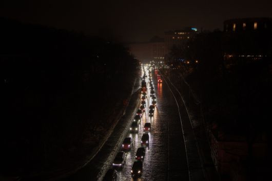 러시아가 27일(현지시간) 우크라이나 키이우에 대규모 공습을 단행한 뒤 키이우내 비상정전 조치가 내려지자 깜깜한 도로 위로 헤드라인을 켠 차량이 이동하고 있다. [AFP]
