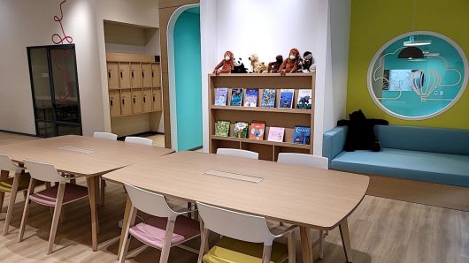 탁자와 의자가 놓여 있고 책장과 소파가 있는 실내 사진이다.책장 위에는 인형들이 진열되어 있다.