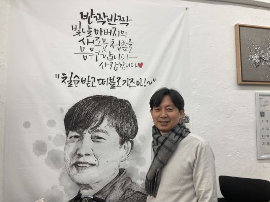 ‘인쇄 분야 서울 명장’ 김인호 동양상사지기인쇄 대표가 아들이 칠순 기념으로 선물한 응원 현수막 앞에서 웃고 있다. 손인규 기자