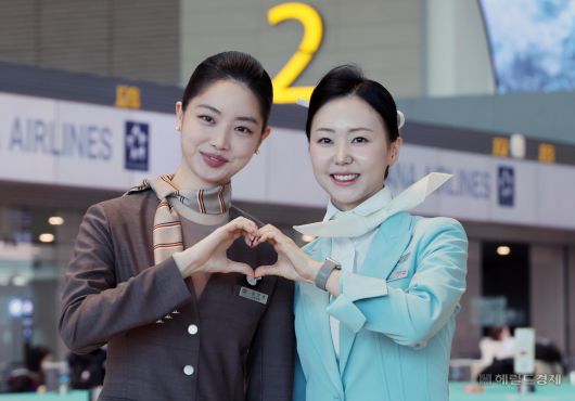 아시아나항공이 인천공항 제2여객터미널(T2)에서 운항을 시작한 14일 대한항공과 아시아나 승무원들이 손 하트를 하며 기념촬영을 하고 있다. 사진=박범준 기자