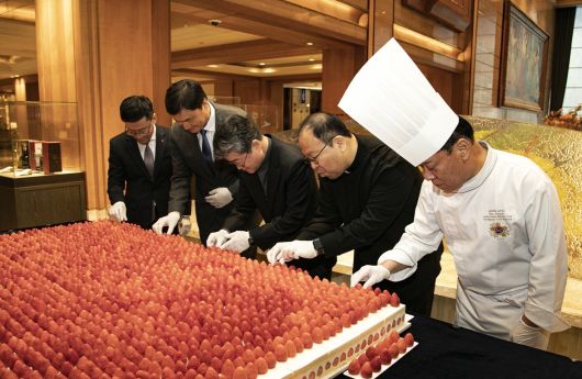 지난 21일 롯데호텔 서울에서 열린 100개의 케이크로 만든 200kg 대형 프리미엄 딸기 케이크 전달식에서 참석자들이 직접 딸기 데코레이션 퍼포먼스에 참여해 대형 케이크를 완성하고 있다. 사진=롯데호텔앤리조트 제공