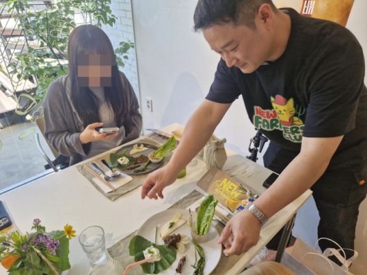 청년농부 정찬수 씨가 팝업 레스토랑 현장에서 손님에게 로메인 새비체 플레이팅을 선보이고 있다. 정씨는 스마트팜 시스템을 활용해 로메인 상추를 재배 중이다./사진=조효정기자