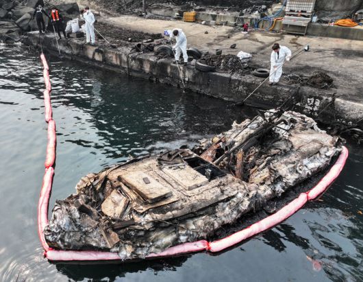 26일 경북 영덕군 영덕읍 노물리 항구에 어선이 산불에 전소된 가운데 해경 관계자들이 부유물 제거 작업을 하고 있다.