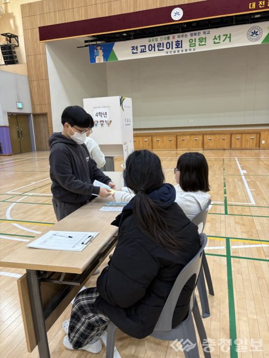 전교 임원 선거에서 학생이 투표용지를 전달하며 직접 선거 절차에 참여하고 있다