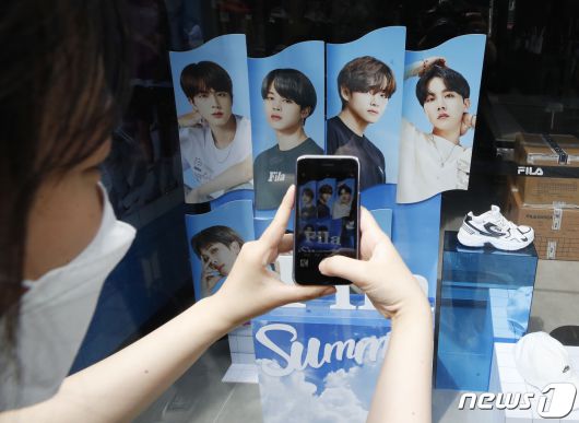7일 오후 서울 중구 명동거리의 한 매장 BTS의 광고판 앞에서 여성팬이 사진을 찍고 있다. 그룹 방탄소년단(BTS) 정국, 지민, RM, 뷔, 제이홉, 슈가, 진은 'Butter'로 미국 빌보드 메인 싱글 차트인 '핫 100'에서 6주째 1위를 지키며 명실상부한 '21세기 팝 아이콘'임을 또다시 입증했다.2021.7.7/뉴스1 © News1 권현진 기자