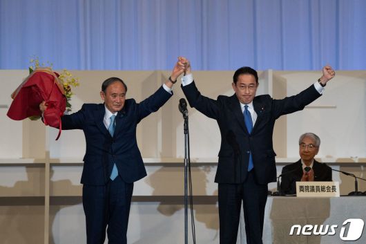 기시다 후미오 신임 자민당 총재(오른쪽)가 29일(현지시간) 도쿄에서 총재에 선출된 뒤 물러나는 스가 요시히데 총리와 손을 잡고 인사하고 있다. 기시다 총재는 내달 초 의회 선출 절차를 거쳐 총리로 정식 취임한다. 2021.9.30/뉴스1 © AFP=뉴스1