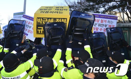 28일 오후 서울 세종대로 외교부 청사에서 기시다 후미오 일본 외무상이 탑승한 차량이 지나가자 경찰이 한일 외교장관회담에 반대하는 시민사회단체 회원들의 피켓을 방패로 가리고 있다. 윤병세 외교부 장관은 이날 기시다 후미오 일본 외무상과 한일 외교장관회담을 열고 일본군 위안부 문제와 관련 최종 합의안을 도출했다. 일본은 아베 신조 총리 명의로 "위안부로서 많은 고통을 갖고 상처입은 분들에게 마음으로부터 깊은 사죄를 표명한다＂고 밝혔다. 양국은 한국 정부가 위안부 피해자들을 지원하기 위한 재단을 설립하고 일측이 10억엔 가량의 정부 예산을 이 재단에 투입하기로 했다. 2015.12.28/뉴스1 © News1 신웅수 기자