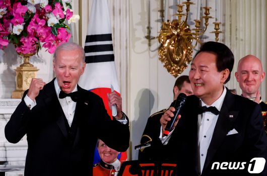 미국을 국빈 방문한 윤석열 대통령이 26일(현지시간) 워싱턴 DC 백악관에서 열린 국빈만찬에서 마이크를 잡고 노래를 부르자 조 바이든 미국 대통령이 양손을 들고 환호하고 있다. 2023.04.26. ⓒ 로이터=뉴스1 ⓒ News1 김성식 기자