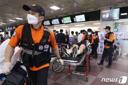26일 오전 제주공항을 출발해 대구공항으로 향하던 아시아나 항공기에서 비행 중 문이 열리는 사고가 발생했다. 울산에서 열리는 제52회 전국소년체육대회에 참가하기 위해 비행기에 탑승했던 초·중학생 제주특별자치도 선수단 가운데 대구공항 도착 직후 고통을 호소하는 선수들을 119구조대가 들것을 이용해 구급차로 옮기고 있다. 2023.5.26/뉴스1 ⓒ News1 공정식 기자