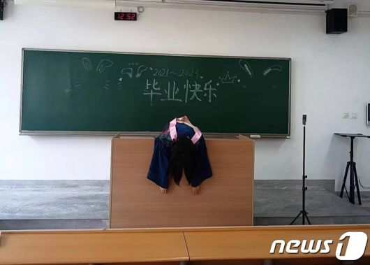 한 대학생이 교탁 위에 축 늘어져 있다. 칠판에는 '졸업축하'라는 글이 쓰여 있다. - 웨이보 갈무리
