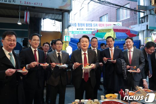 윤석열 대통령이 6일 부산 중구 깡통시장을 방문해 기업인들과 떡볶이를 시식하고 있다. 왼쪽부터 최재원 SK 수석부회장, 이재용 삼성전자 회장, 조현준 효성 그룹 회장, 윤 대통령, 구광모 LG그룹 회장, 김동관 한화그룹 부회장, 정기선 HD현대 부회장. (대통령실 제공) 2023.12.6/뉴스1 ⓒ News1 오대일 기자