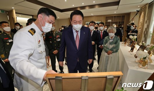 윤석열 대통령이 작년 6월9일 서울 용산 대통령실 청사에서 열린 '호국영웅 초청 소통식탁' 행사에 참석, 제2연평해전에 참전한 이희완 국가보훈부 차관 내정자(당시 해군 중령)으로부터 사진설명을 듣고 있다. (대통령실사진기자단) 2022.6.9/뉴스1 ⓒ News1 안은나 기자