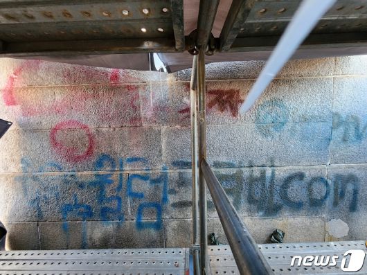 17일 서울 종로구 경복궁 영추문 입구 벽이 낙서로 훼손돼있다. 경찰에 따르면 서울 종로경찰서 청운파출소에 지난 16일 오전 2시20분쯤 경복궁 담이 낙서로 훼손됐다는 신고가 접수됐다. 담에는 빨간 스프레이와 파란 스프레이로 '영화꽁짜'라는 문구와 불법 영상 공유 사이트로 보이는 문구가 적혔다. 인근 CCTV 등을 통해 용의자를 추적중인 경찰은 문화재보호법 위반 혐의 적용 여부를 검토중이다. 2023.12.17./뉴스1 ⓒ News1 박세연 기자