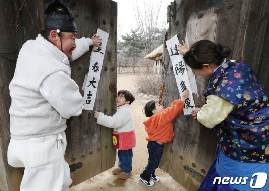절기상 입춘(立春)을 사흘 앞둔 1일 경기 용인시 기흥구 한국민속촌에서 직원들과 아이들이 입춘대길(立春大吉)과 건양다경(建陽多慶)이라고 적은 입춘첩을 대문에 붙이고 있다. 입춘대길과 건양다경은 '봄이 시작되니 크게 길하고 경사스러운 일이 많이 생기길 기원한다'는 의미를 갖고 있다. 2024.2.1/뉴스1 ⓒ News1 김영운 기자