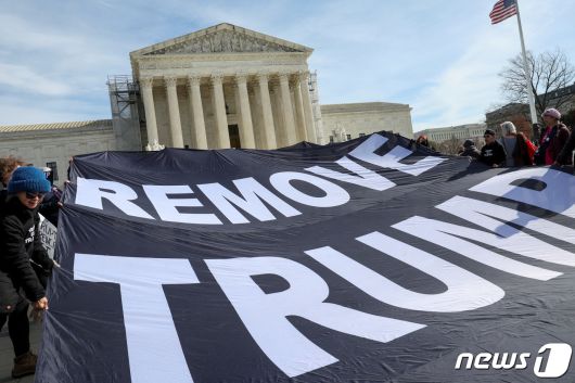 미국 워싱턴DC 연방대법원에서 8일(현지시간) 도널드 트럼프 전 미국 대통령의 콜로라도주 대선후보 자격 박탈 여부에 대한 재판이 열린 가운데, 일부 활동가들이 트럼프 전 대통령의 대선후보 자격 박탈을 요구하는 현수막을 들고 있다. 2024.02.08. ⓒ 로이터=뉴스1 ⓒ News1 김현 특파원