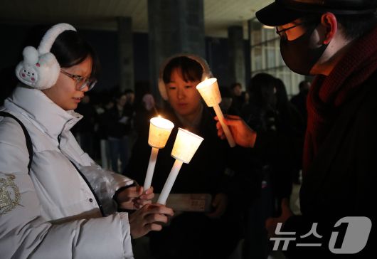 5일 서울 관악구 서울대학교 아크로폴리스 광장에서 열리는 전체총학생회에 참석하는 학생들이 촛불을 들고 입장하고 있다. 윤석열 대통령 퇴진 요구를 안건으로 열리는 이번 전체총학생회는 서울대 전체 학부생의 1/10인 약 2000명이 참석해야 성사된다. 2024.12.5/뉴스1 ⓒ News1 임세영 기자