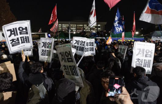 윤석열 대통령의 비상계엄 해제 요구 결의안이 국회 본회의에서 통과된 4일 새벽 서울 여의도 국회 정문 앞에 모인 시민들이 모여 있다. 여야는 이날 본회의에서 재석 190명 중 찬성 190명으로 비상계엄 해제 요구 결의안을 가결 처리했다. 이에 따라 계엄령 선포는 무효가 됐다고 국회의장실은 설명했다. 2024.12.4/뉴스1 ⓒ News1 이재명 기자