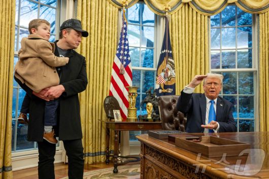 도널드 트럼프 미국 대통령이 11일(현지 시간) 워싱턴 백악관에서 행정명령에 서명을 하며 아들을 안은 일론 머스크 정부효율부(DOGE) 수장과 얘기를 하고 있다. 2025.02.12 ⓒ AFP=뉴스1 ⓒ News1 우동명 기자
